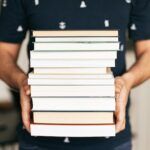 a photo of a person holding a stack of books
